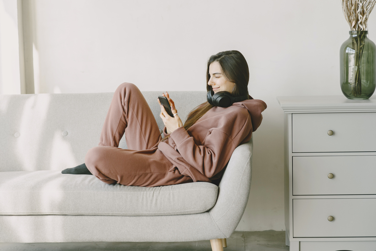 Woman with Headphones Using Smartphone on the Sofa